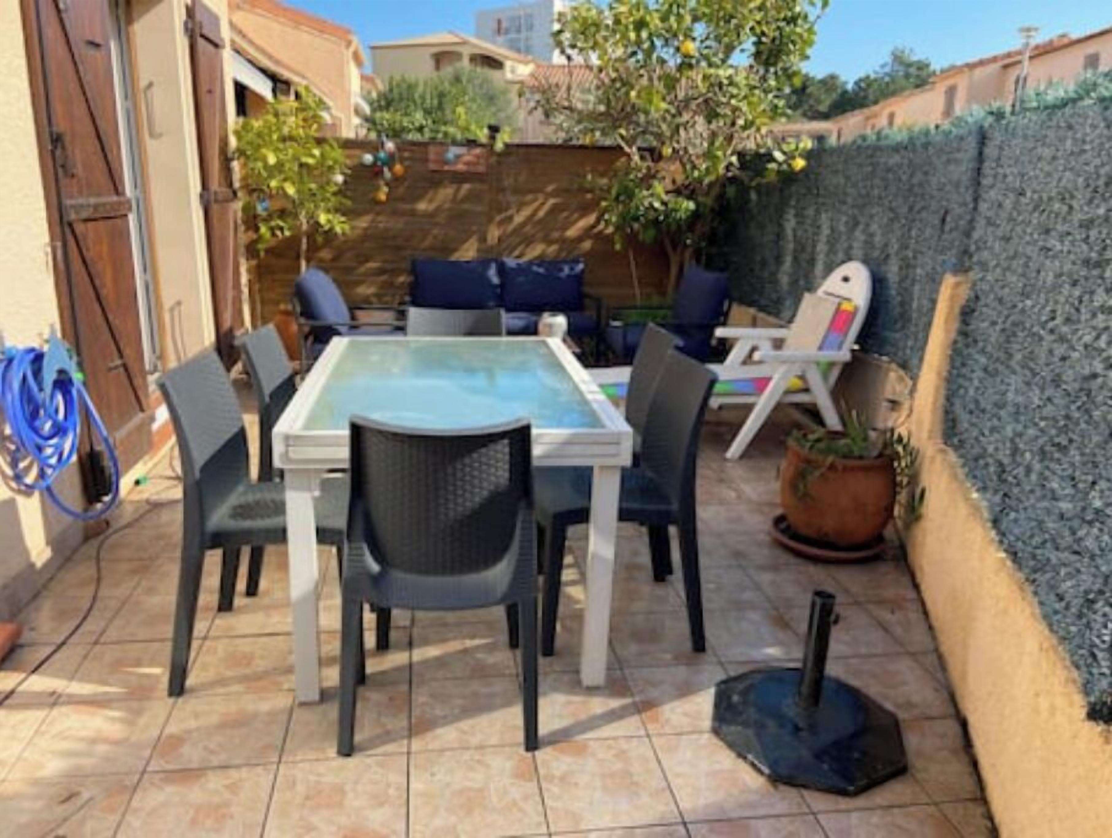 Eine Terrassenausstattung mit Tisch aus Glasplatte, sechs Stühlen und einem Blumentopf.