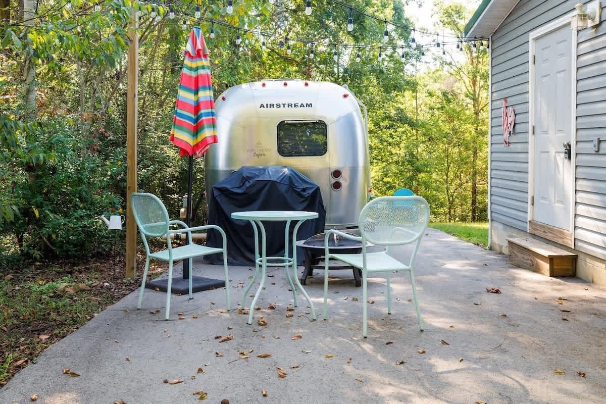 A trailer with a covered table and two chairs in a backyard.