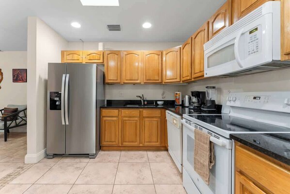 A kitchen with wooden cabinets, a stainless steel refrigerator, a microwave, a stove, and a dishwasher. - 5BR Family Oasis w/ Pool, Near Beach & Downtown (Hollywood)