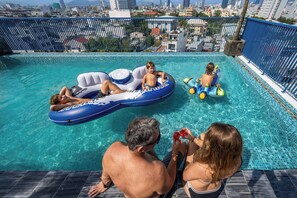 A rooftop pool with clear blue water, surrounded by a blue fence, and overlooking a cityscape. - Dana Boutique Hotel & Apartment (Da Nang)