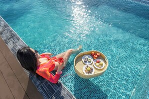 A person relaxing by a poolside with a basket of snacks. - Dana Boutique Hotel & Apartment (Da Nang)