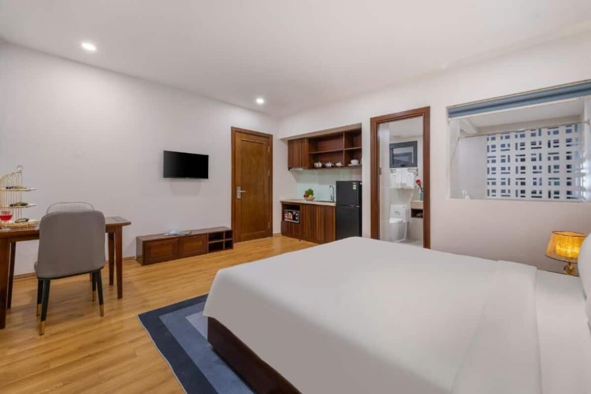 Ein Hotelzimmer mit Bett, Schreibtisch, Stuhl, Fernseher, einer Küchenzeile und einem Fenster mit Blick.