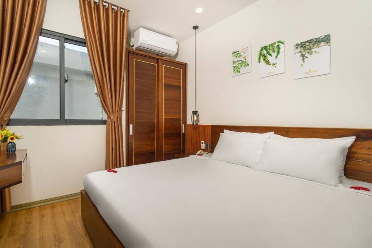 Ein Hotelzimmer mit einem großen Bett, einem Holzschrank und einem Fenster mit Vorhängen.
