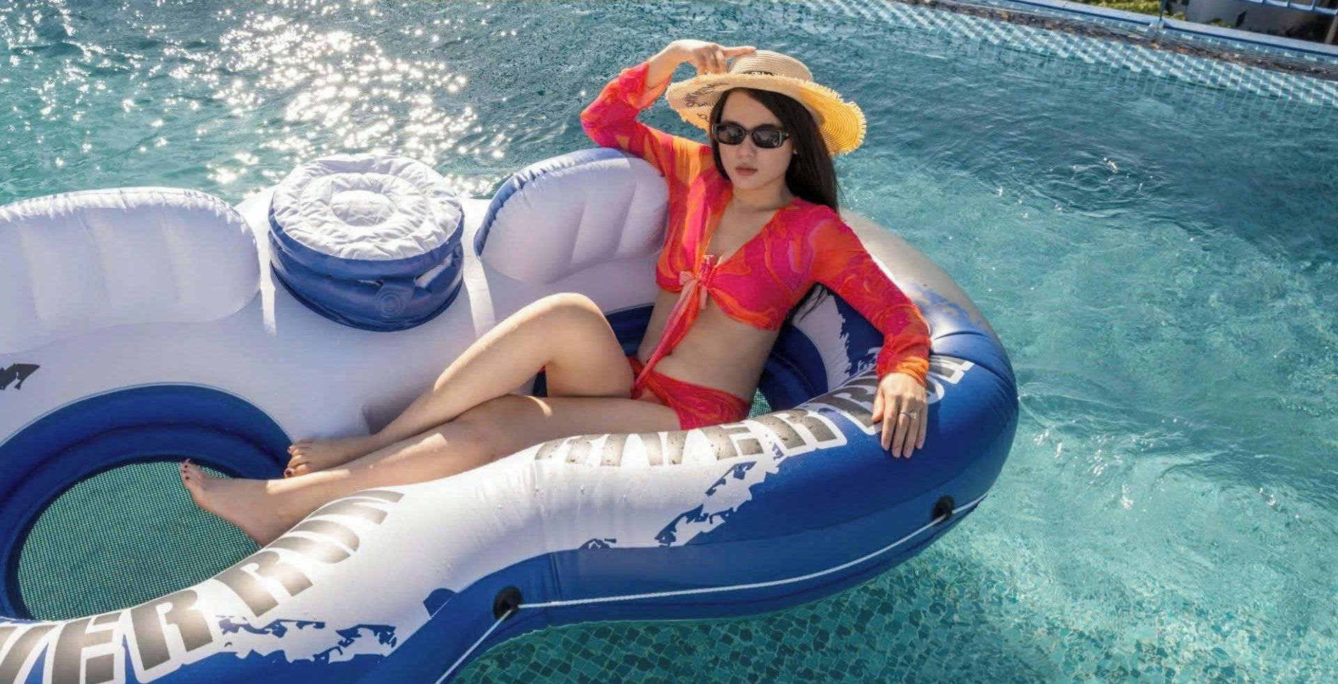 Une personne se détend dans une piscine, allongée sur un flotteur gonflable, et une clôture entoure la piscine.