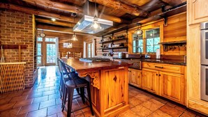 Una cocina rústica con armarios de madera, una isla grande y una pared de ladrillo.