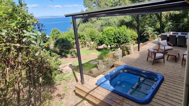 A wooden deck with a hot tub, outdoor furniture, and a view of the sea. - Magnificent house sea view- Jacuzzi- 2Ha land- GR34 (Poullan-sur-Mer)