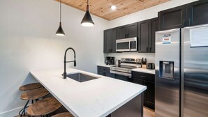 A modern kitchen with a white marble countertop, stainless steel appliances, and dark cabinetry.