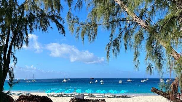 Uma praia com águas azul-claras, barcos e guarda-sóis.