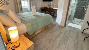 Quarto com cama, luminária de cabeceira e escrivaninha com cadeira.