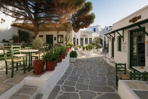 A courtyard with stone flooring, green chairs, and potted plants. - Charming White House Retreat with Balcony in Paros Lefkes (Lefkes Paros)