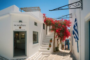 A narrow street with white buildings, a sign for 'scarabee JEWELLERY WORKSHOP', and a blue door. - Charming White House Retreat with Balcony in Paros Lefkes (Lefkes Paros)