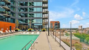 A modern building with a rooftop pool, lounge chairs, and a view of the cityscape. - High-Rise Apt Raleigh Free Parking & Sunset View 2 (Raleigh)