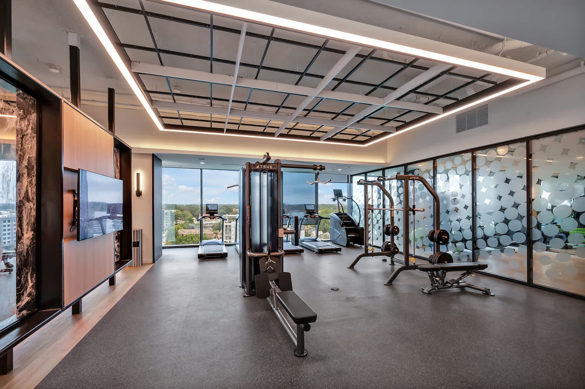 Une salle de sport moderne dotée d’une grande fenêtre, d’appareils d’exercice et d’un banc.