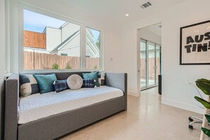 Un salon moderne avec un canapé gris, une grande fenêtre et un panneau décoratif encadré accroché au mur.