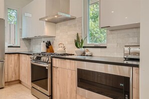 Une cuisine moderne équipée d’une cuisinière à gaz, d’un four et d’un micro-ondes encastré.