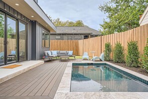 Un espace piscine extérieur moderne, doté d’une terrasse en bois, d’un coin salon intégré et d’une clôture en bois.
