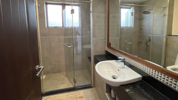 Une salle de bain moderne avec une douche à parois de verre, un lavabo blanc et un grand miroir.