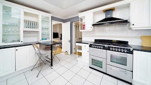 A kitchen with white cabinets, a black countertop, and a gas stove. - Charming 3-Bedroom Bungalow in London (Greater London)