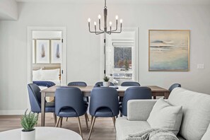 Un espace de repas moderne agrémenté d’un lustre, d’un canapé et d’un tableau au mur.