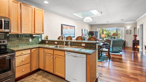 A modern kitchen with wooden cabinets, a dishwasher, and a dining area with a table and chairs. - Pet-Friendly Top-Floor Downtown Carbondale Retreat with A/C, Views & Walkable Main Street (Carbondale)