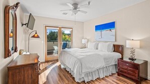 A bedroom with a bed, a ceiling fan, a painting, a desk, and a chair. - Pet-Friendly Top-Floor Downtown Carbondale Retreat with A/C, Views & Walkable Main Street (Carbondale)