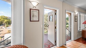 A hallway with a view of the outside, a framed picture on the wall, and a red rug leading to a door. - Pet-Friendly Top-Floor Downtown Carbondale Retreat with A/C, Views & Walkable Main Street (Carbondale)