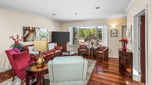 A living room with a sofa, armchairs, a coffee table, and a TV. There is a window with a view of trees and a lamp on a side table. - Pet-Friendly Top-Floor Downtown Carbondale Retreat with A/C, Views & Walkable Main Street (Carbondale)