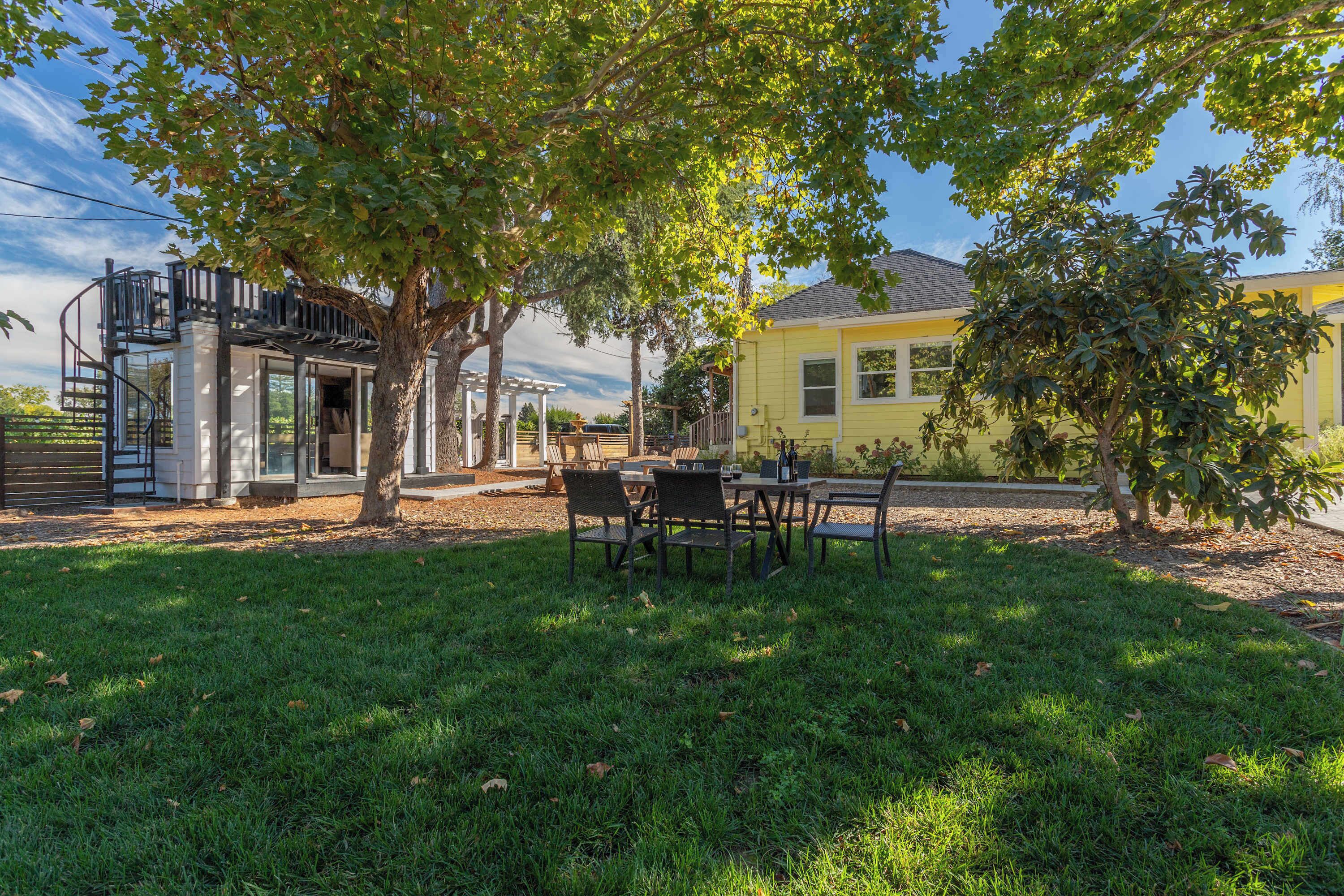 A residential property with a patio, outdoor seating, a staircase, and a yellow house.