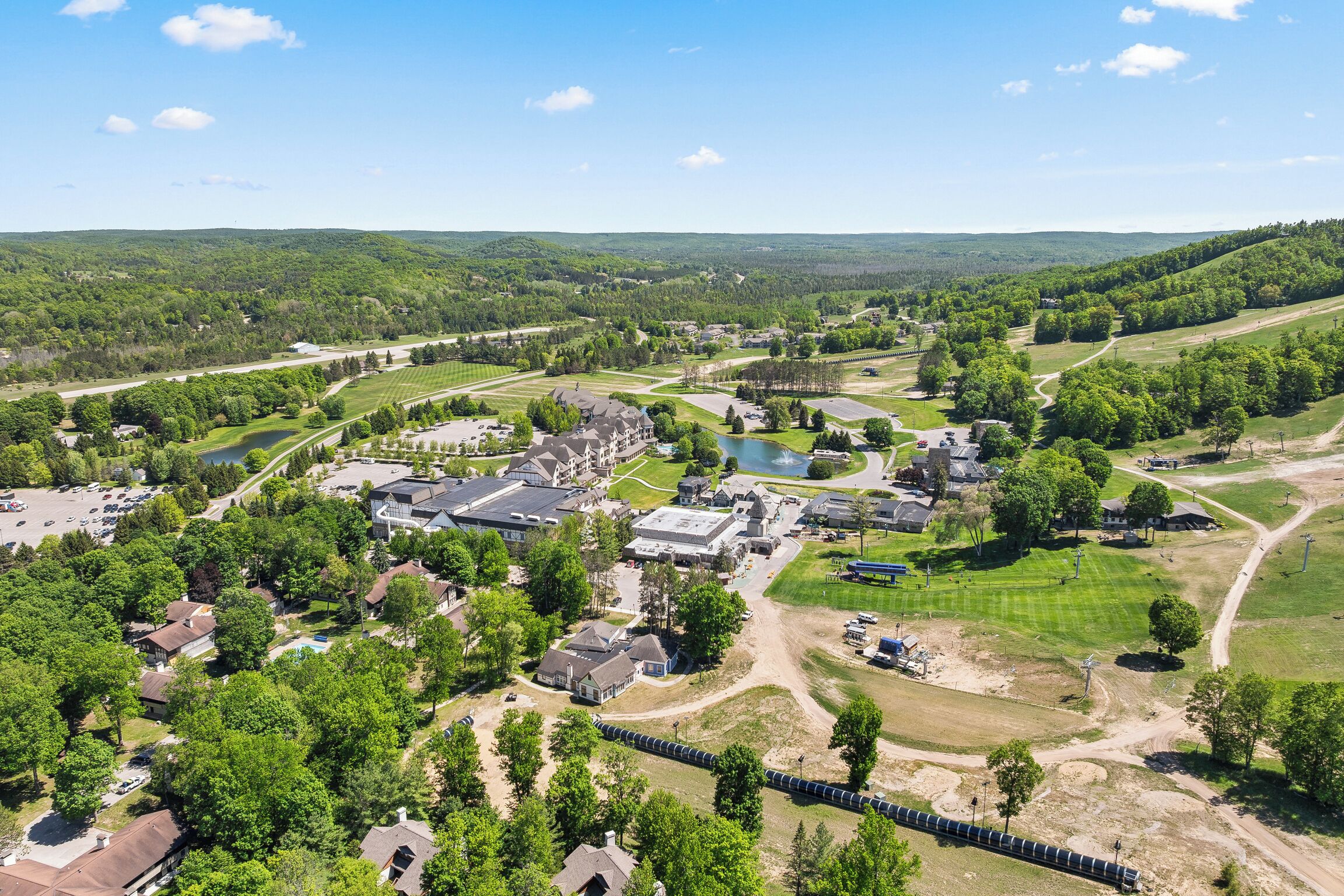 An aerial view of a residential area with houses, a large building complex, and a lake.