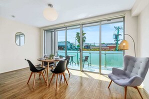 Un espace repas moderne avec une table ronde, quatre chaises et une grande fenêtre donnant sur un balcon.