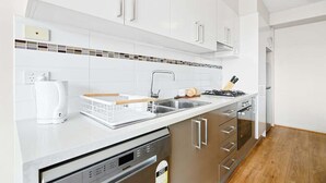 A modern kitchen with white cabinets, a stainless steel sink, and a dishwasher.