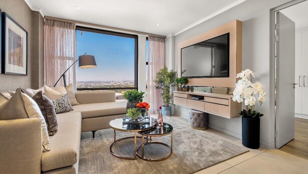 A modern living room with a sofa, coffee table, and TV. - Modern 2-bedroom Executive apartment with WiFi, in Masingita Towers Sandton (Sandton)