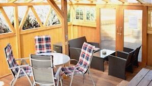 Eine Holzterrasse mit Korbmöbeln, darunter Stühle und ein Tisch.