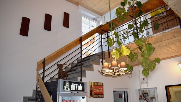 Eine Treppe mit einer Holzhandläufe, ein Coca-Cola-Automaten und ein Schild, das den Verkauf von eiskaltem Coca-Cola anzeigt.
