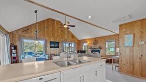 A spacious kitchen with a large island, wooden walls, and a ceiling fan. - Prime Location, Short Walk To The Beach, Water Views, Sun Deck (Rodanthe)