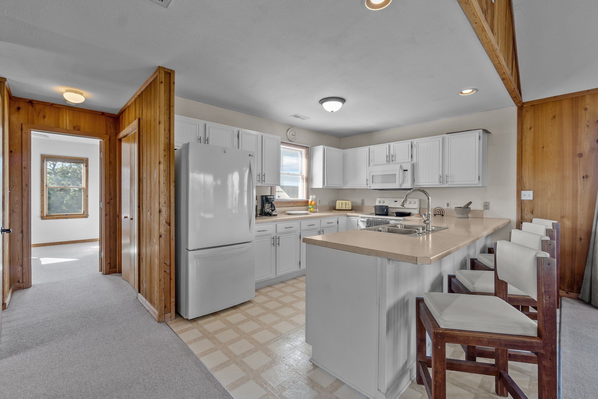 Una cocina moderna con armarios blancos, una isla central y detalles de madera.