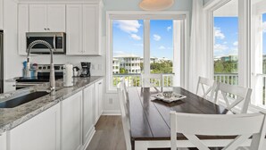 Una cocina moderna con armarios blancos, un microondas integrado y un amplio ventanal con vistas a una zona residencial.