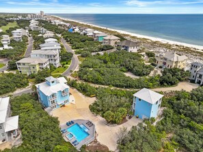 Un quartier résidentiel avec des maisons, une piscine et une plage en arrière-plan.