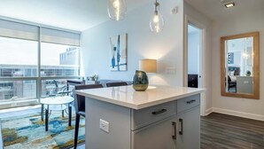 A modern kitchen with a large island, pendant lights, and a view of the city through large windows. - Luxury Apt Near Downtown (Stamford)