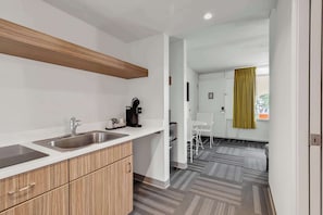 A modern kitchen with a double sink, wooden cabinets, and a coffee maker.