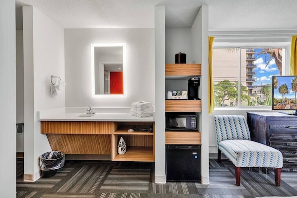 A modern bathroom with a vanity, mirror, and a view of a tropical landscape.