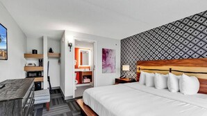 Een hotelkamer met een bed, een bureau, een stoel, een kleine kitchenette en een badkamer.