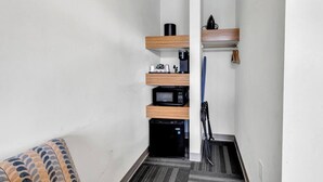A narrow hallway with a microwave, coffee maker, and a small refrigerator on a shelf. - Holiday Shores King Bed 209 (Myrtle Beach)