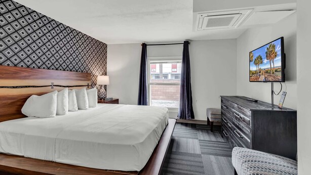 Ein Hotelzimmer mit Bett, Fernseher, Kommode und einem Vorhangfenster.