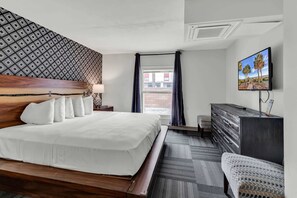 A hotel room with a bed, a TV, a dresser, and a window with curtains. - Holiday Shores King Suite 214 (Myrtle Beach)