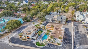 An aerial view of a hotel with a swimming pool, multiple buildings, and a parking lot.