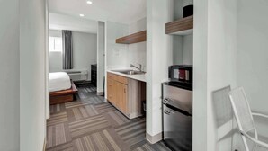 Una habitación de hotel moderna con cama, kitchenette y un pequeño comedor.