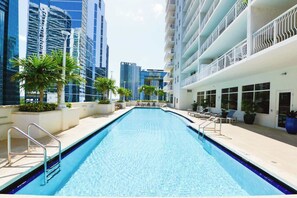 A swimming pool with a clear blue water surface, surrounded by high-rise buildings and palm trees. - 1BR Brickell | Free Parking | Metromover Access (Miami)