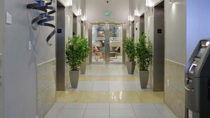 A hotel corridor with a clean, tiled floor, potted plants, and a visible exit door. - 1BR Brickell | Free Parking | Metromover Access (Miami)