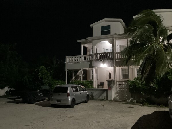A two-story building with a balcony and a car parked in front. - Colwins #4 For Families/Couples/Singles Sleeps 4 (Grand Turk)